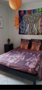 a bedroom with a purple bed with a painting on the wall at Chambres chez l'habitant ZAMBROKAL in Bois dʼOlive