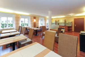 a restaurant with wooden tables and chairs and windows at Hotel Garni Benser Watt in Bensersiel