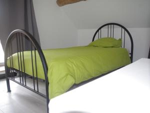 een zwart metalen bed met groene lakens en kussens bij La Grangette En Bourgogne in Saint-Sernin-du-Plain