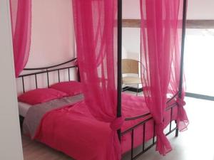 een roze hemelbed met roze gordijnen in een kamer bij La Grangette En Bourgogne in Saint-Sernin-du-Plain