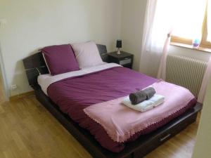 Saint-Léger-sur-DheuneにあるLa Conciergerie du Manoirのベッド1台(紫のシーツとタオル2枚付)