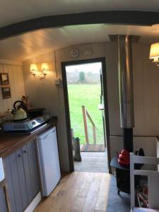 a kitchen with a door leading to a yard at Charming Shepherds Hut with Wood Fired Hot Tub in Charlton Musgrove