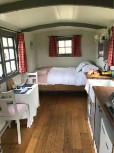 a bedroom with a bed and a table and a kitchen at Charming Shepherds Hut with Wood Fired Hot Tub in Charlton Musgrove