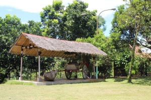 a pavilion with a cart with a straw roof at Kampoeng Wisata Rumah Joglo in Bogor