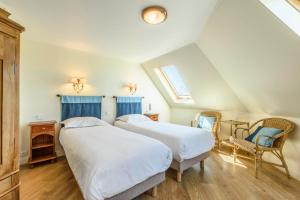 two beds in a attic bedroom with blue curtains at Hotel Le Clos Fleuri in Le Palais