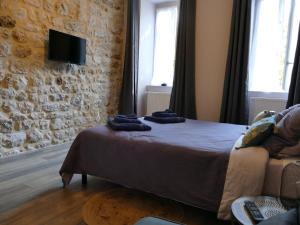 ein Schlafzimmer mit einem Bett und einer Steinmauer in der Unterkunft Au Pied de la Béalière in Montpezat-sous-Bauzon