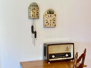 a television sitting on a table with clocks on the wall at Ferienwohnungen im Eugenhaus in Rosenfeld