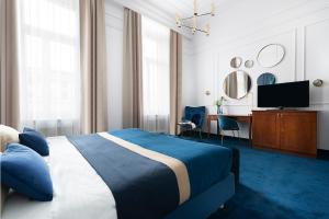 Schlafzimmer mit einem Bett, einem Schreibtisch und einem TV in der Unterkunft IBB Hotel Grand Hotel Lublin in Lublin