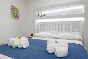 una camera da letto con un grande letto bianco con asciugamani di ELORO - Guest Houses a Noto