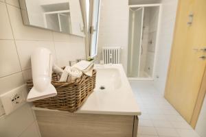 uma casa de banho branca com um lavatório e um espelho em Relais Emilei em Verona