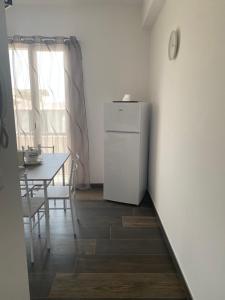 a white refrigerator in a kitchen with a table at B&B Libertà in Pachino