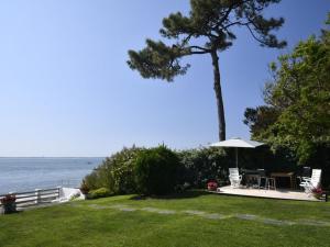 césped con sombrilla, mesa y sillas en Villa De La Plage, en Pyla-sur-Mer