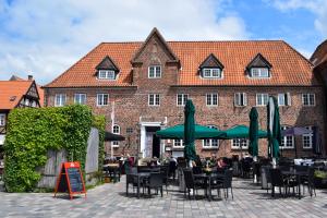 a restaurant with tables and green umbrellas in front of a building at Hotel Dagmar in Ribe
