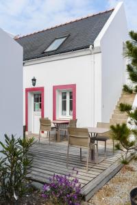 a white house with a wooden deck with a table and chairs at Hotel Le Clos Fleuri in Le Palais