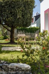 a garden with a table and chairs under a tree at Hotel Le Clos Fleuri in Le Palais