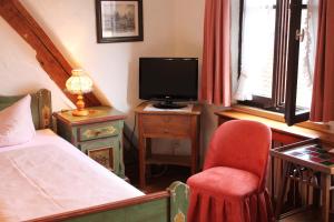 a bedroom with a bed and a chair and a television at Hotel Spitzweg in Rothenburg ob der Tauber