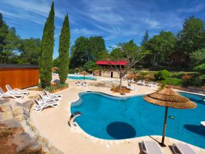 - Piscina en un complejo con sillas y sombrilla en la Truffière Saint Cirq Lapopie en Saint-Cirq-Lapopie