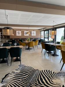 - un hall avec des tables, des chaises et un tapis zébré dans l'établissement Le Regina Hôtel restaurant, à Hardelot-Plage