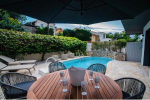 einem Holztisch mit Stühlen und einem Sonnenschirm neben einem Pool in der Unterkunft Villa de Charme La Lionne-Piscine-12 pers in Saint-Raphaël