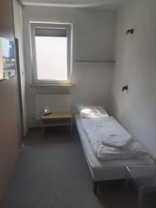 a small room with a bed and a window at OperaHostel in Bydgoszcz