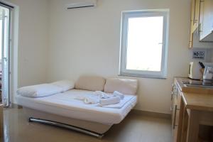 a white couch in a kitchen with a window at Apartment Noel in Novalja