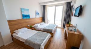 een hotelkamer met 2 bedden en een televisie bij Hotel Besani in Durrës