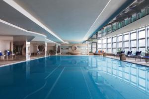 a large swimming pool with blue water in a building at Beijing Pudi Hotel in Beijing