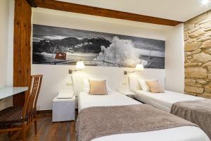 a hotel room with two beds and a painting on the wall at Pension Aida in San Sebastián