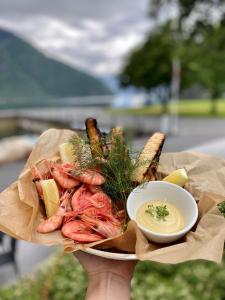 eine Person, die einen Teller mit Meeresfrüchten und eine Schüssel Dip-Soße hält in der Unterkunft Klingenberg Hotel in Årdalstangen