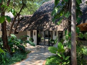 um edifício com um telhado de palha e uma passagem em Pamarah Lodge em Victoria Falls