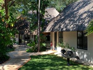 een huis met een rieten dak en een pad bij Pamarah Lodge in Victoria Falls