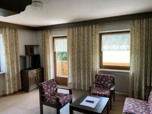 a living room with chairs and a table and windows at Appartments Hilber in Brunico