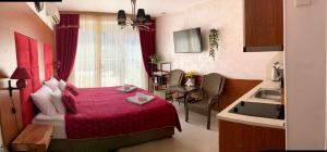 a bedroom with a red bed and a kitchen at Luxury Premium przy samym Morzu Plaży in Primorsko