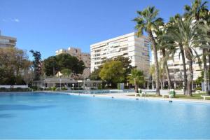 ein großer Pool mit Palmen und Gebäuden in der Unterkunft Garden apartment with Pool and AC in Alicante