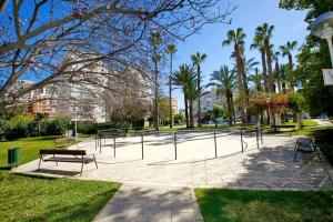 einen Park mit Bänken in einem Park mit Palmen in der Unterkunft Garden apartment with Pool and AC in Alicante
