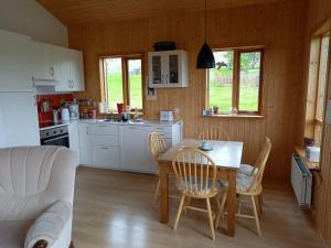 uma cozinha e sala de estar com mesa e cadeiras em Kópareykir Cottage em Reykholt