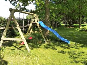 a swing set with a blue slide in the grass at Landhaus Aballo - Ferienwohnung in grüner Oase mit Ruhe und Komfort in Utarp