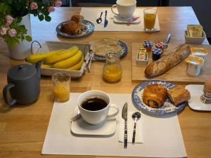 a table with a breakfast of bread and coffee and bananas at Auprès du château in Brézé +2 photos