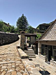 a stone pathway leading to a house with a stone wall at Konaki Hotel in Papigko