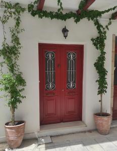 a red door on a white wall with two plants at Lefkas Central in Lefkada Town
