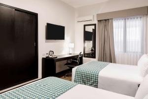 a hotel room with two beds and a desk at Costa del Sol Wyndham Piura in Piura