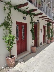 a red door on a white building with potted plants at Lefkas Central in Lefkada