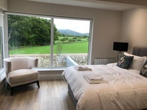 a bedroom with a large window and a bed and a chair at Hilltown Lodges No5 in Hilltown