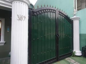 a green gate with two columns next to a house at Mint Homes in CEV Mansion in Manila