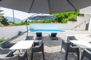 un patio con tavoli, sedie e ombrellone di Gemma di Cattaro Apartments a Kotor (Cattaro)