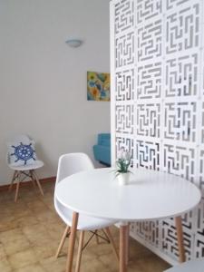 einen weißen Tisch und Stühle in einem Zimmer mit einer Wand in der Unterkunft Casa Vacanze Mazzini in Santa Maria al Bagno