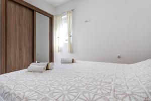 a white bedroom with a large bed with two pillows on it at Apartments LungoMare in Tivat