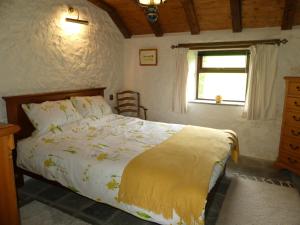 a bedroom with a bed with a yellow comforter and a window at Silverstripe in Turriff