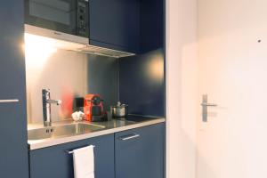 a kitchen with blue cabinets and a sink at HITrental Allmend Standard Studios in Luzern