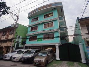 a blue building with cars parked in front of it at Mint Homes in CEV Mansion in Manila